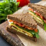Vegan sandwich with salad and cheese, ondark stone background, copy space